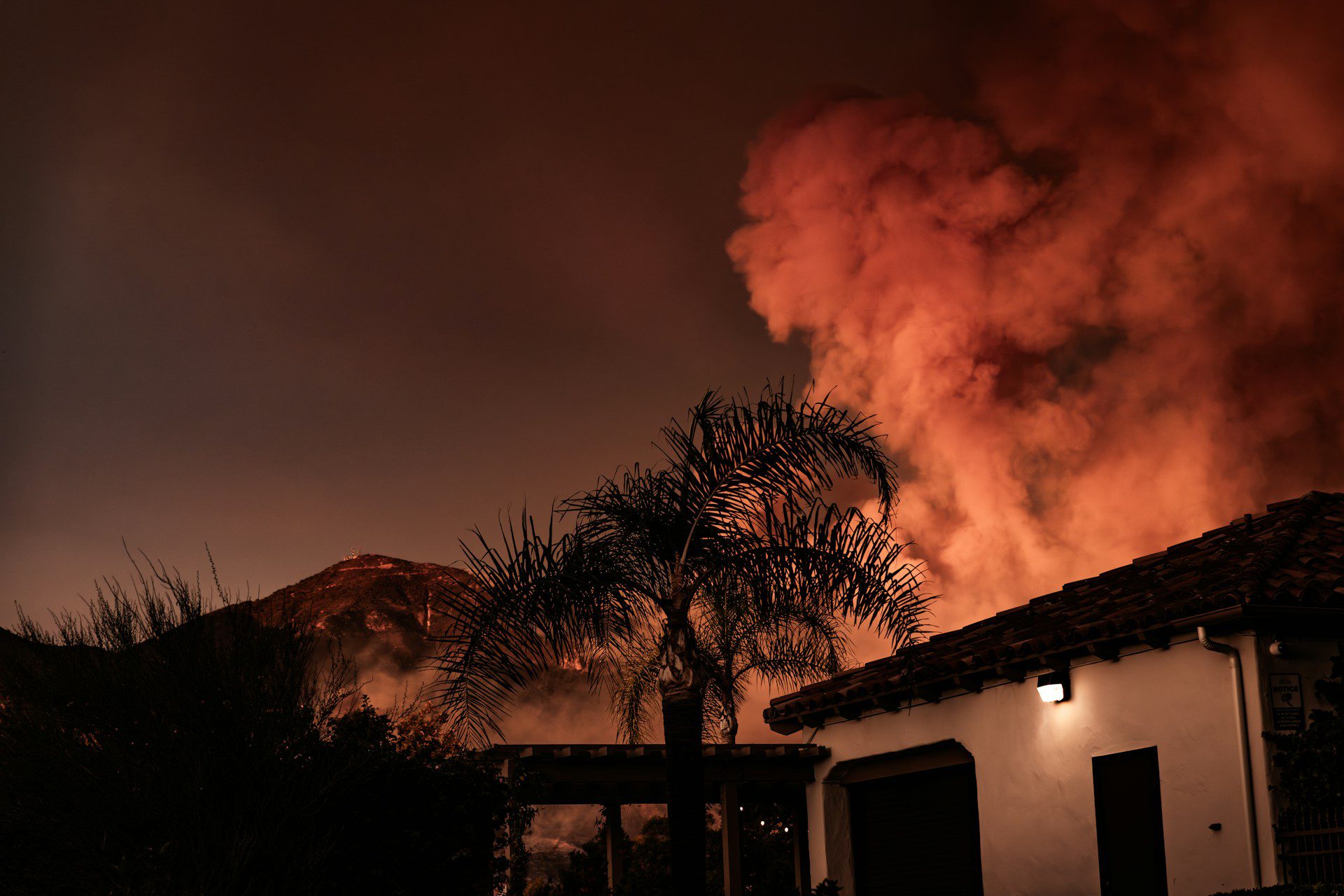 A shot looking up at a large cloud of smoke coming from a building and a mountain in the distance.